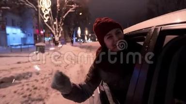 年轻快乐的女人站在车<strong>窗外</strong>，在<strong>下雪</strong>的冬夜玩着火花。 漂亮女孩开车很有趣